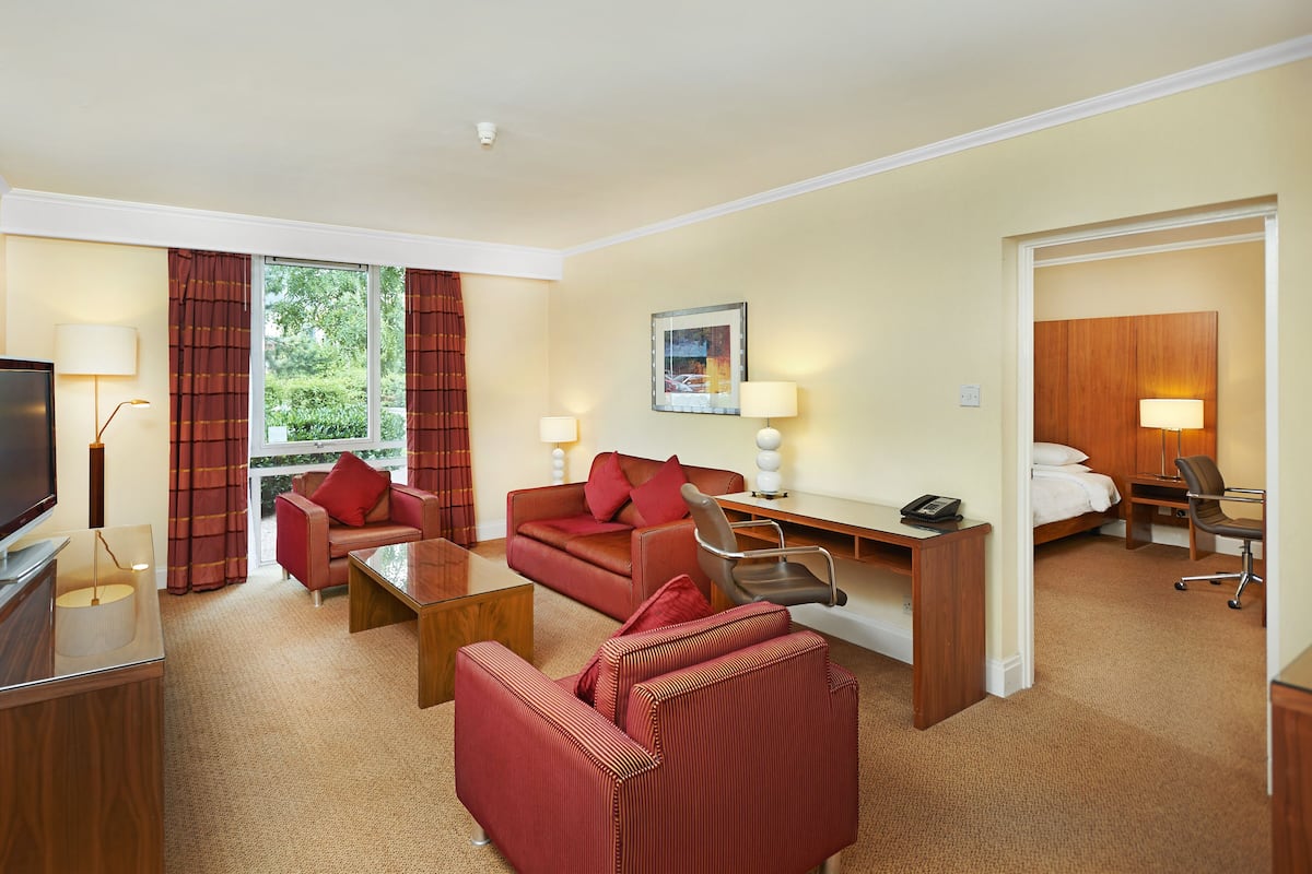 Ein Hotelzimmer mit Fernseher, Schreibtisch, Sofa und Bett.