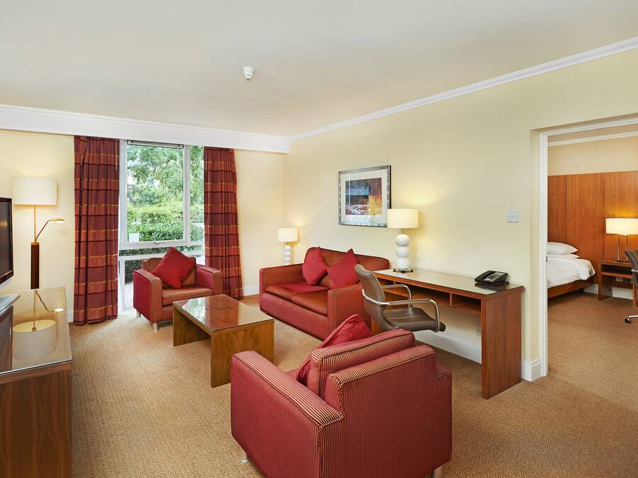 A hotel room with a TV, a desk, a sofa, and a bed.