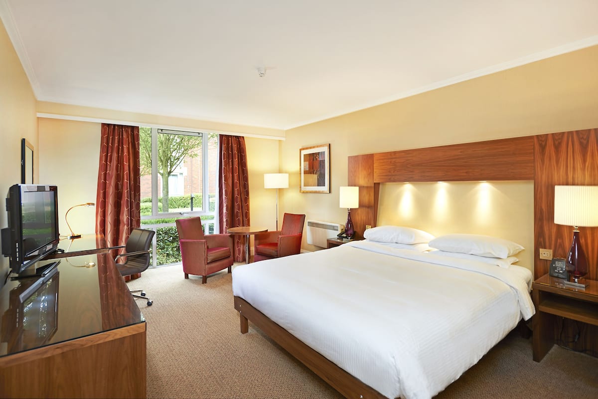 Ein Hotelzimmer mit Bett, Schreibtisch, Stuhl, Lampen und einem Fernseher.