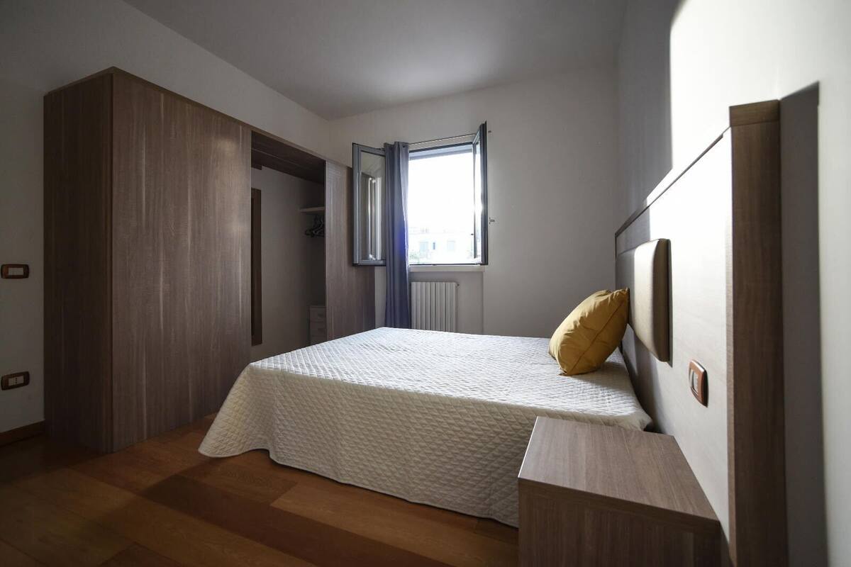 Een slaapkamer met een bed, een kledingkast en een raam.