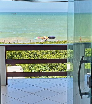 A balcony with a view of the sea, a glass railing, and a tiled floor. - Beira Mar Itaipava (Itaipava)
