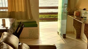 Ett modernt vardagsrum med en soffa i läder, ett soffbord i glas och utsikt över havet genom ett stort fönster.