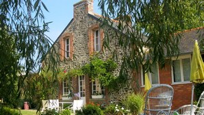 A stone building with a garden, outdoor seating, and a yellow umbrella. - Seaside house in large enclosed garden in Binic (Binic-Étables-sur-Mer)
