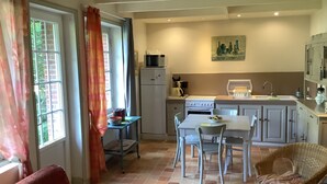 A cozy kitchen with a dining area, featuring a table, chairs, a refrigerator, and a stove. - Seaside house in large enclosed garden in Binic (Binic-Étables-sur-Mer)