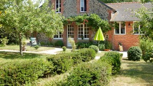 A stone house with a brick facade, a green umbrella, and a well-maintained garden. - Seaside house in large enclosed garden in Binic (Binic-Étables-sur-Mer)