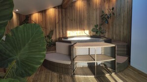 Un moderno espacio de spa con hidromasaje, asientos de mimbre y paredes de madera.