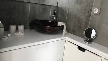 Une salle de bain moderne avec un grand lavabo sur pied, un miroir rond et un plan de toilette blanc.