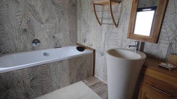 A bathroom with a bathtub, a sink, and a wooden vanity.