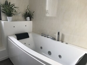 Un baño moderno con una bañera independiente, una toalla negra y dos plantas en macetas.