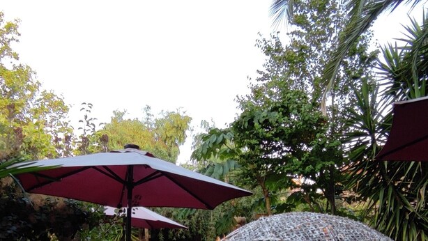 Un patio al aire libre con muebles de mimbre y una estructura de sombrilla decorativa.
