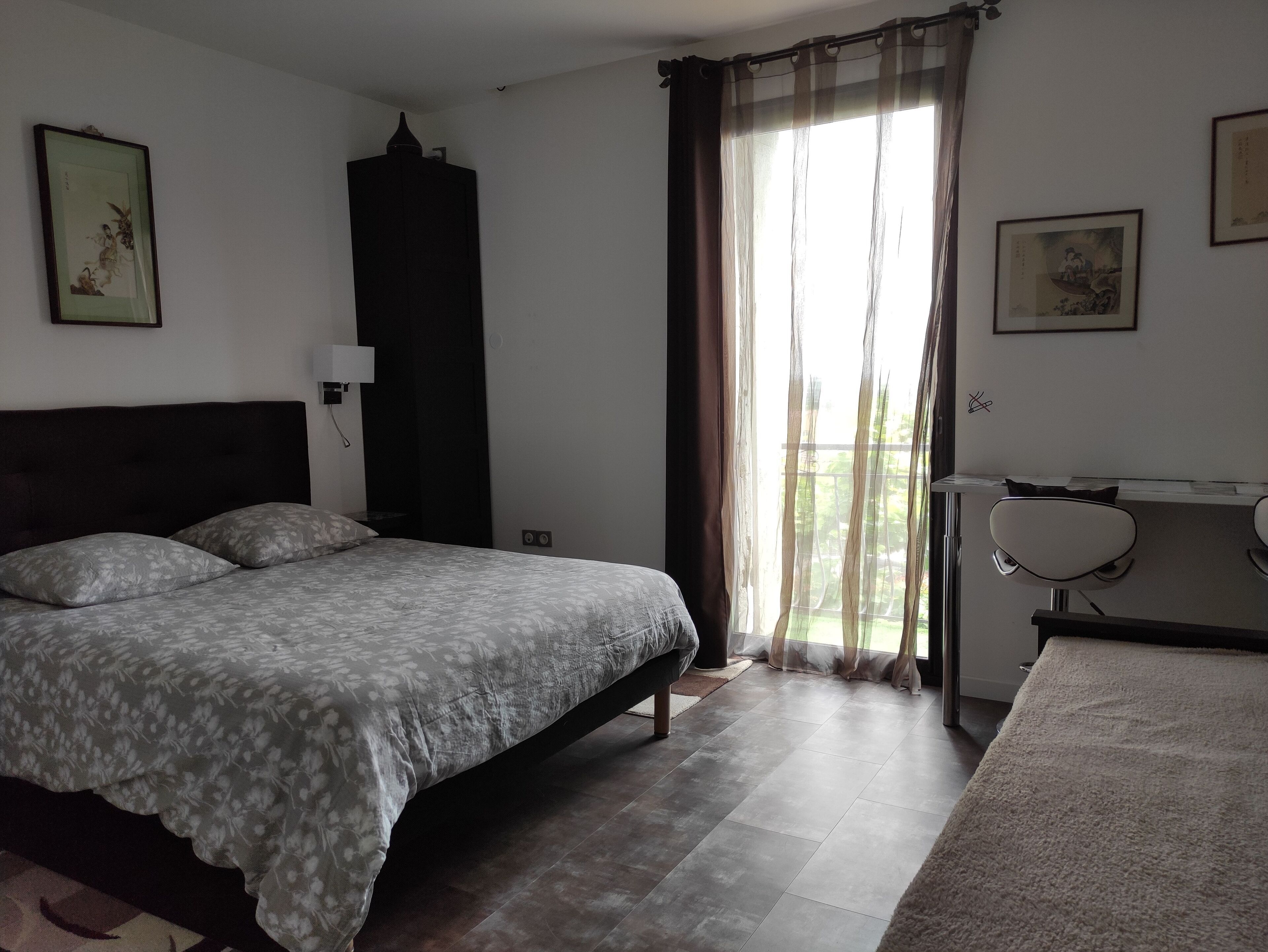 Un dormitorio con cama, escritorio, silla y ventana con cortinas.