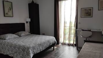 Un dormitorio con cama, escritorio, silla y ventana con cortinas.