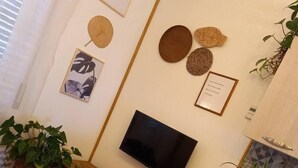 Una sala de estar moderna con un televisor de pantalla plana, un sofá negro, una mesa de centro de madera y una pequeña mesa redonda con un signo de interrogación.
