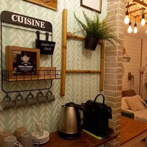 A kitchenette area with a coffee pod station, a kettle, and a shelf with mugs and a tea set. - An Oasi for Traveller Close to the Lake and Lugano (Porto Ceresio)