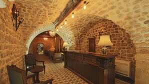 Un hall d’entrée aux murs en pierre, avec un comptoir d’enregistrement, un espace salon et un sol à motifs.