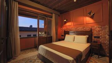 A hotel room with a large bed, a brick wall, and a view through a sliding door.