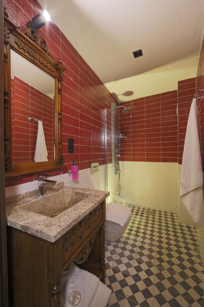 Une salle de bain avec un meuble-lavabo en bois, un grand miroir, un espace douche et un carrelage à carreaux.