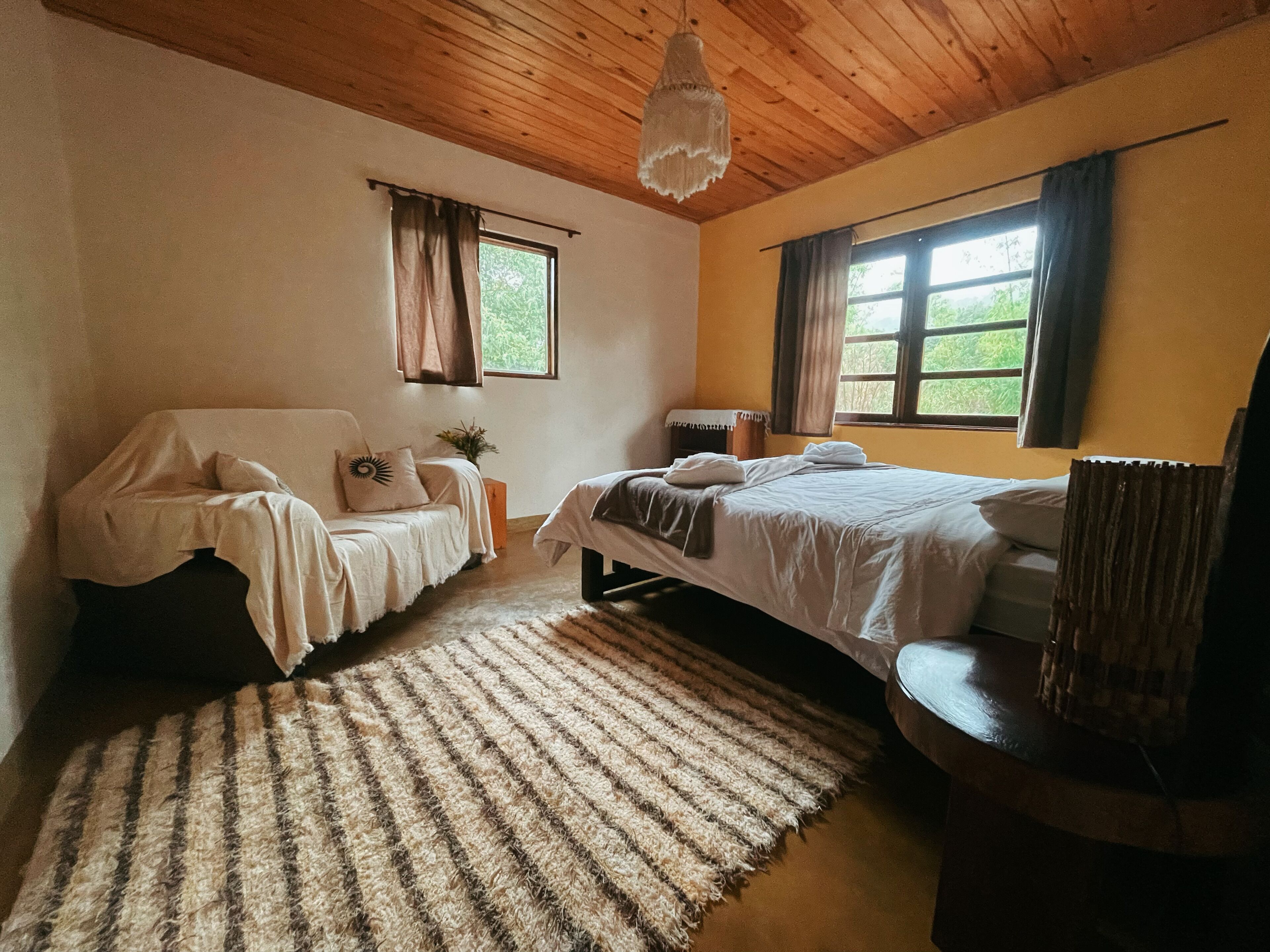Ein gemütliches Schlafzimmer mit zwei Betten, Holzboden und großen Fenstern.