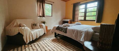 Ein gemütliches Schlafzimmer mit zwei Betten, Holzboden und großen Fenstern.