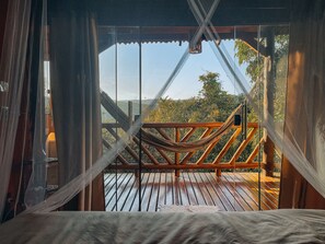 Una hamaca en una terraza de madera con vista a un paisaje montañoso.