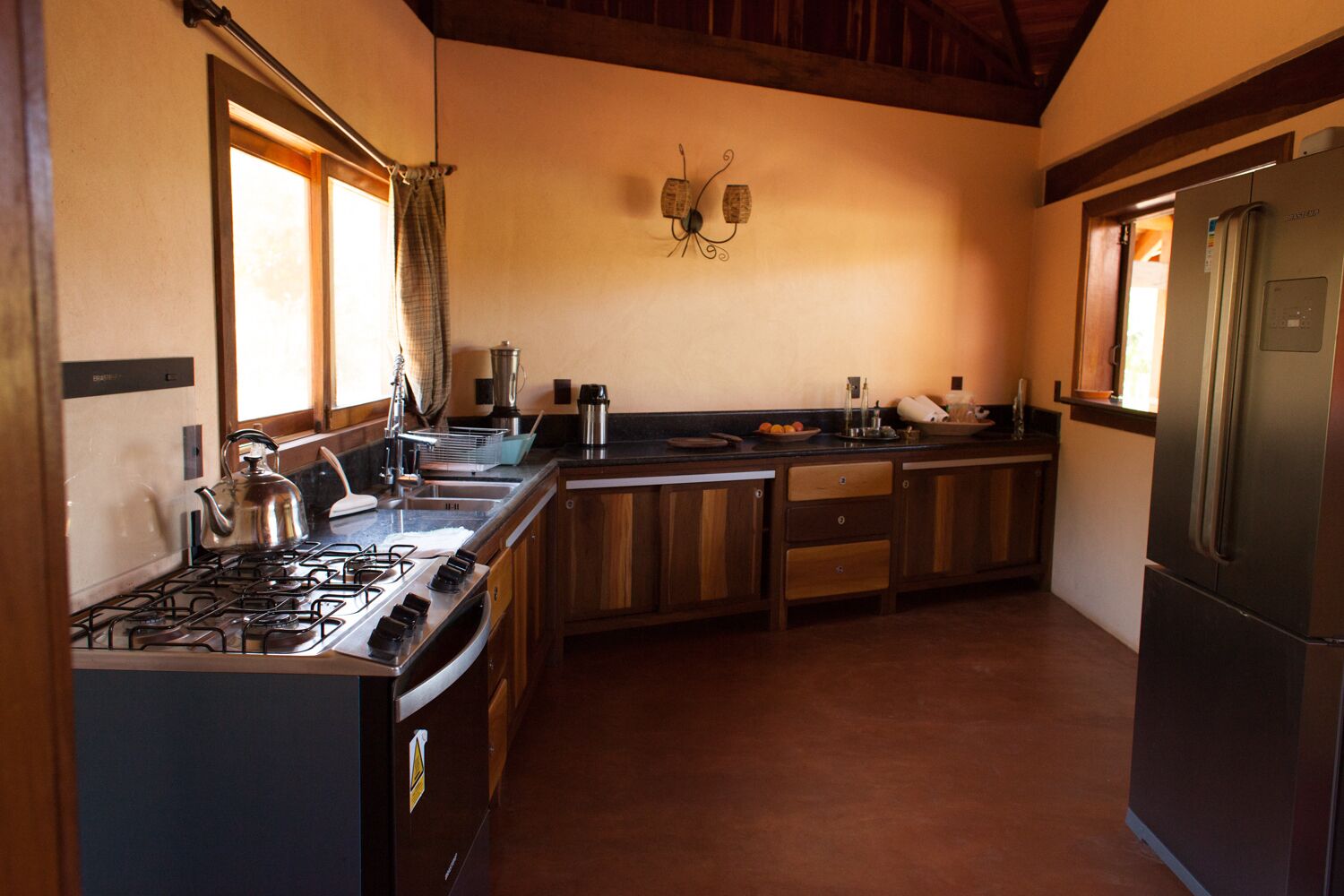 Une cuisine équipée d’une cuisinière à gaz, d’appareils électroménagers en acier inoxydable, de meubles de rangement en bois et d’un réfrigérateur encastré.