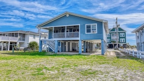 A two-story house with a balcony, a covered porch, and a staircase leading to the upper level. - Inlet Joy 2nd Row Channel Front (Garden City Beach)