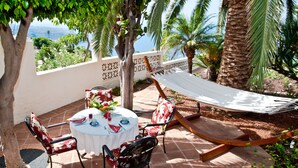Eine Terrasse mit einem runden Tisch, Stühlen und einer Hängematte.