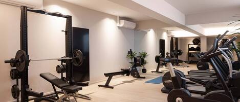 A modern gym with various exercise equipment, including a bench press, a squat rack, and cardio machines.