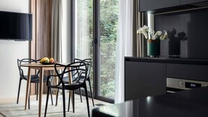 Una cocina moderna con horno integrado, un comedor con mesa y sillas, y un amplio ventanal con vista a zonas verdes.