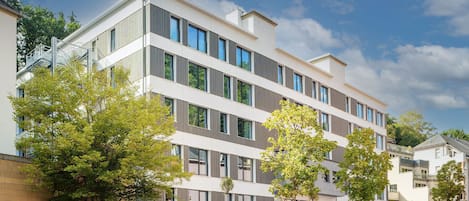 Un immeuble moderne à plusieurs étages, doté d’un toit plat, de grandes fenêtres et d’une façade en briques.