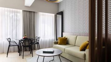 Ein modernes Wohnzimmer mit einer Couch, einem Couchtisch, einem Esstisch mit Stühlen und einer Wand mit Muster.