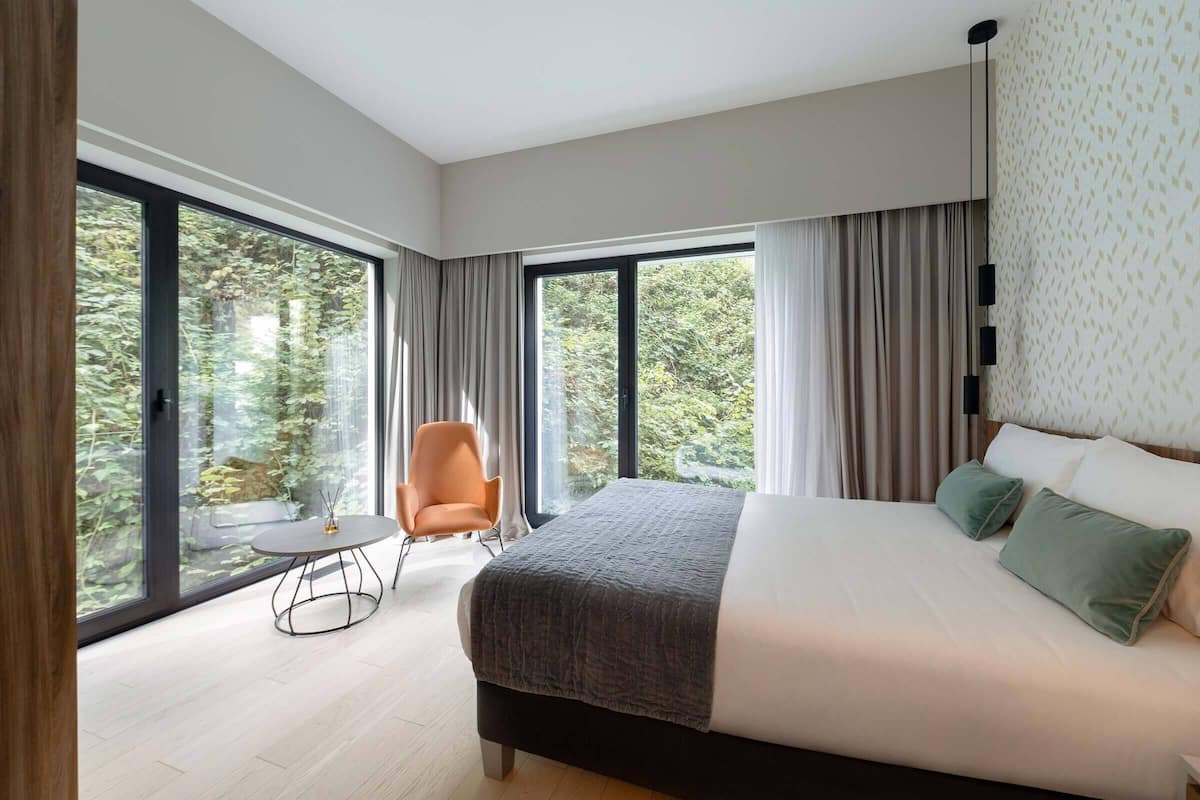 A modern bedroom with a large bed, a round table, and a chair.