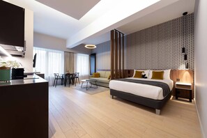 Una habitación de hotel moderna con una cama grande, un escritorio, una zona de comedor y vistas a la ciudad.