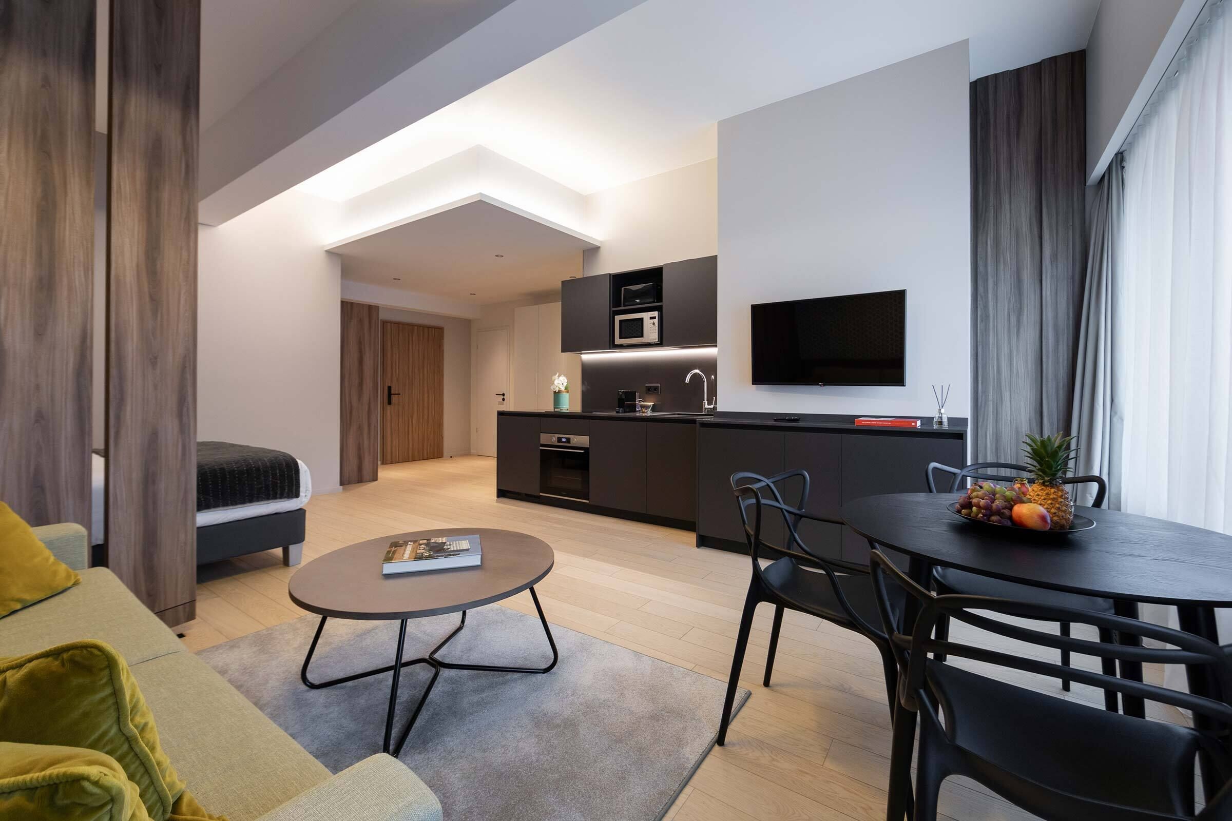 A modern apartment with a living area, kitchenette, and dining space.
