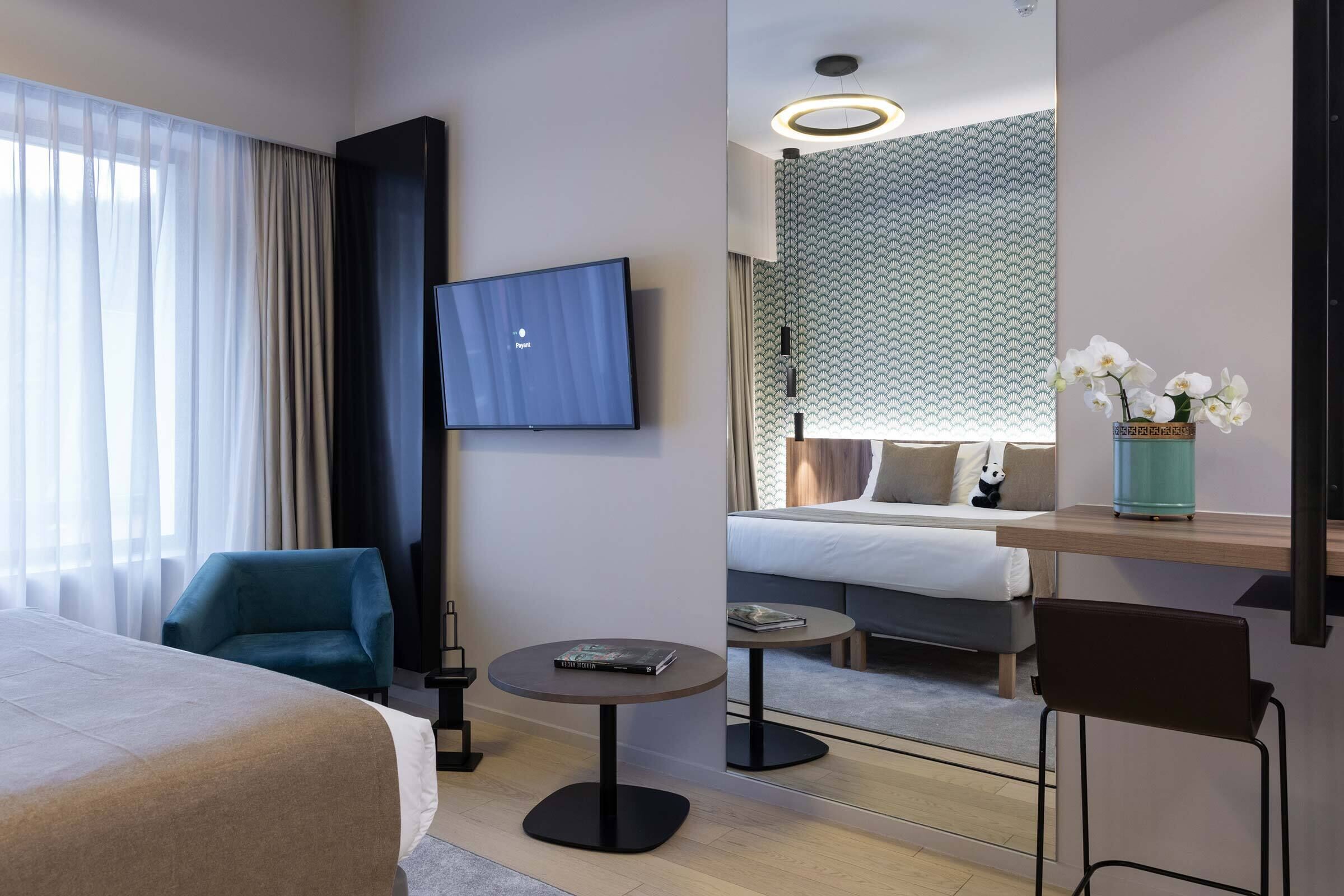 Una habitación de hotel con cama, televisor, escritorio, silla y sofá.