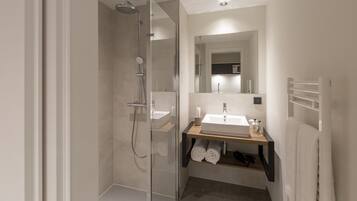 A modern bathroom with a glass-enclosed shower, a sink with a mirror above, and a towel rack.