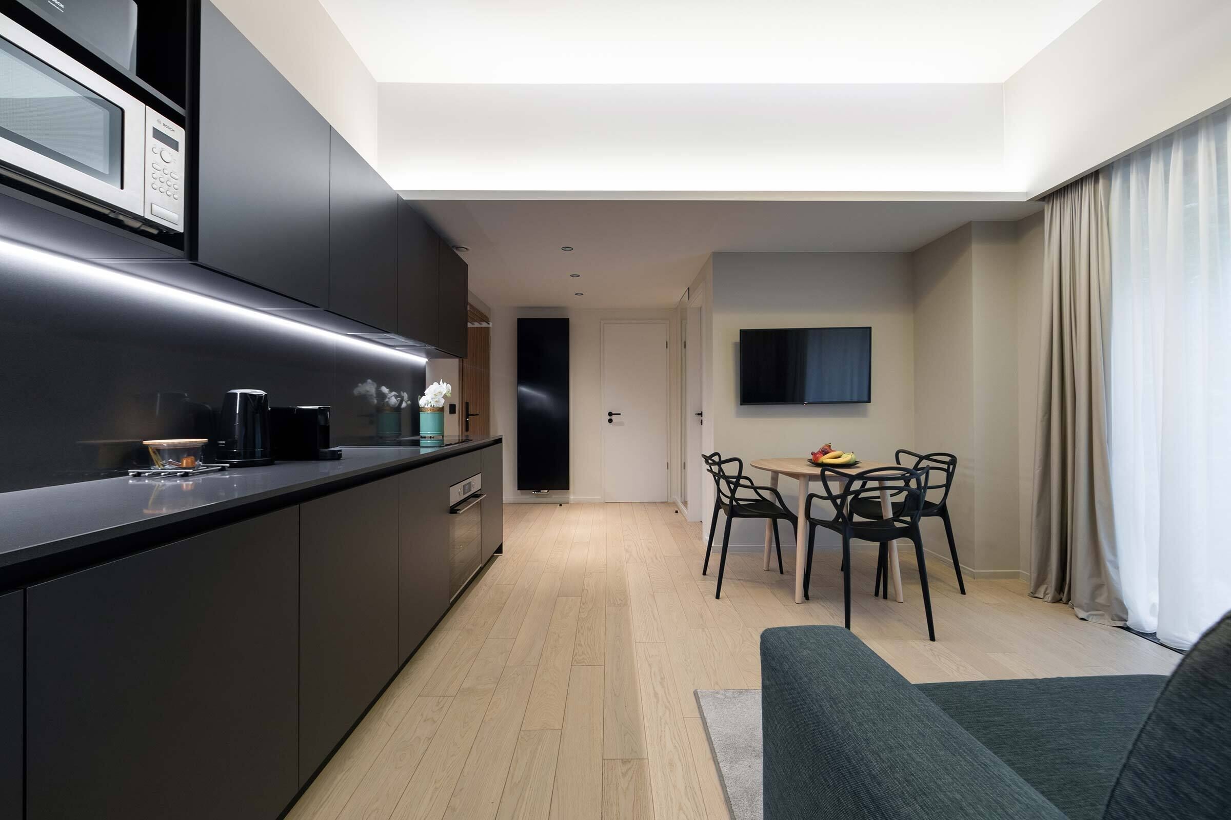 A modern kitchen with a built-in microwave and a dining area with a table and chairs.