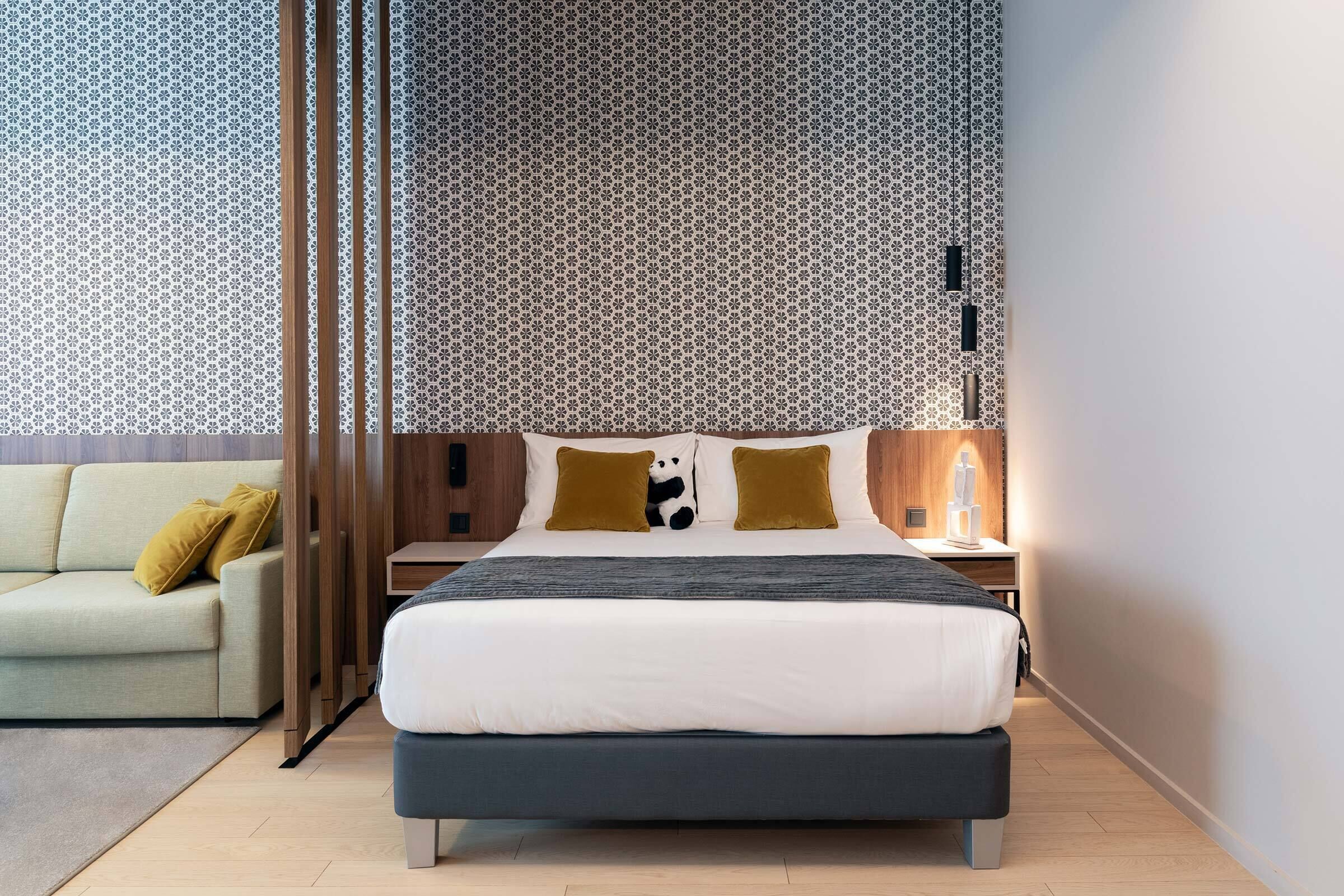 Een moderne hotelkamer met een groot bed, een bank en een behangen muur.