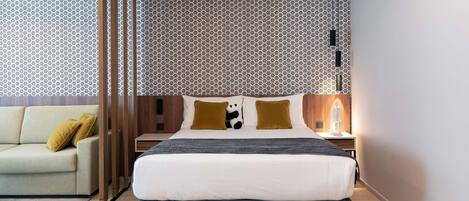 Una habitación de hotel moderna con una cama grande, un sofá y una pared con estampado.