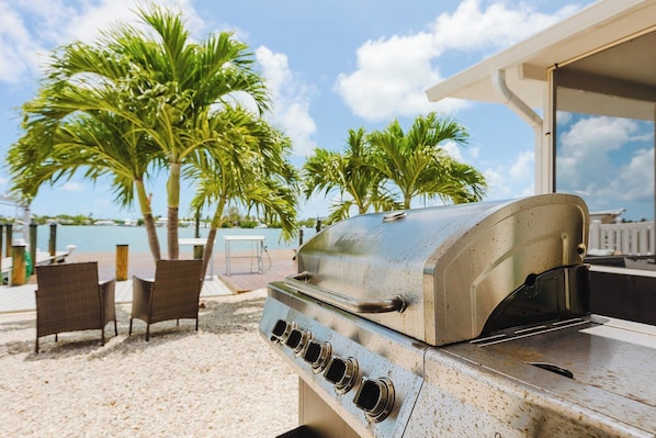 A barbecue grill with a view of palm trees and a body of water.