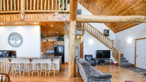 Een ruime woonkamer met een houten trap, een bar en een gezellige zithoek.