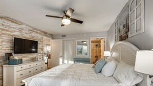 Een slaapkamer met een bed, een dressoir, een televisie en een plafondventilator.