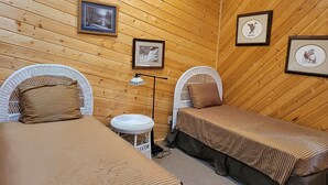 Um quarto aconchegante com duas camas, uma mesinha e quadros nas paredes.
