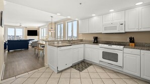 A modern kitchen with white cabinets, granite countertops, a built-in oven, and a microwave. - Adagio - side unit in ofront bldg, 3br/3bath indoor pool (Ocean City)