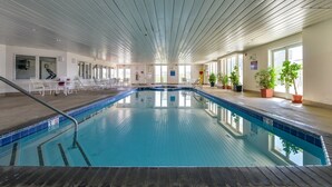 An indoor swimming pool with clear blue water, surrounded by lounge chairs and potted plants. - Adagio - side unit in ofront bldg, 3br/3bath indoor pool (Ocean City)