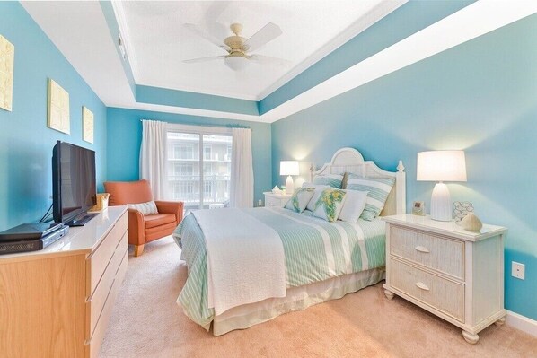 A bedroom with a bed, nightstand, dresser, and a television.