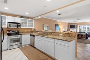 A modern kitchen with white cabinets, granite countertops, stainless steel appliances, and a large island.