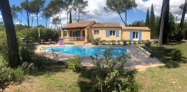 A house with a swimming pool, surrounded by trees and greenery.