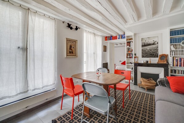 A room with a dining table, chairs, a fireplace, and a sofa.