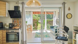 A modern kitchen with a built-in oven and a dining area with a table and chairs. - Charming T2 apartment near the sea - Residence with trees and swimming pool (Le Pradet)